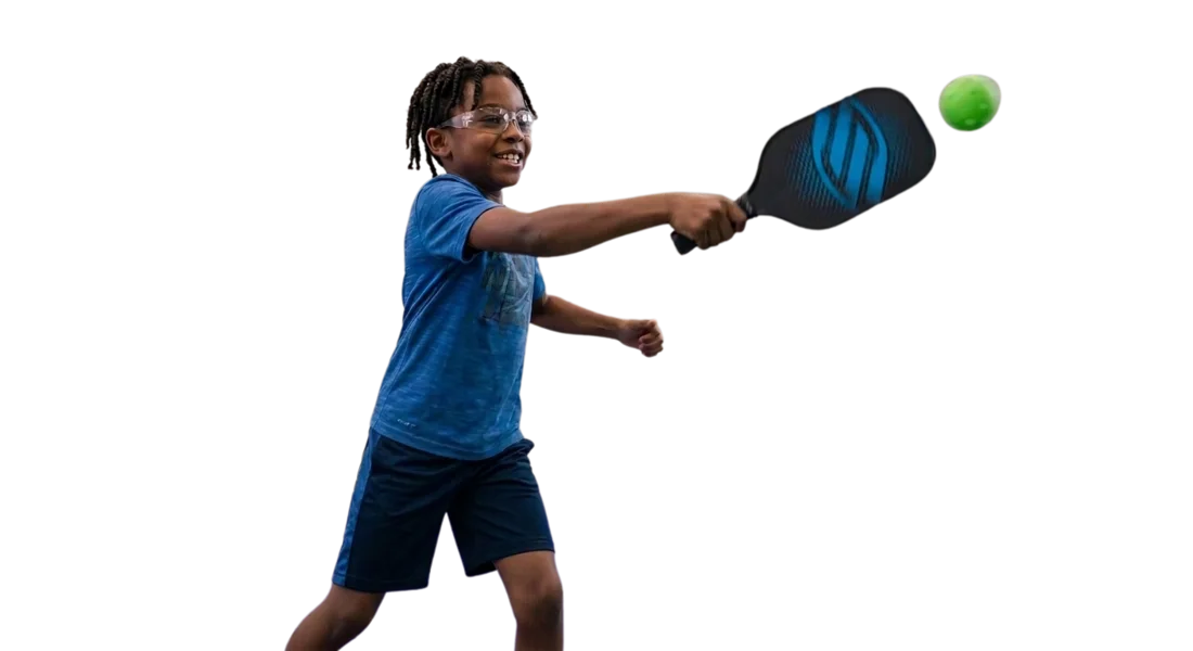 Kid mid-swing hitting a pickleball